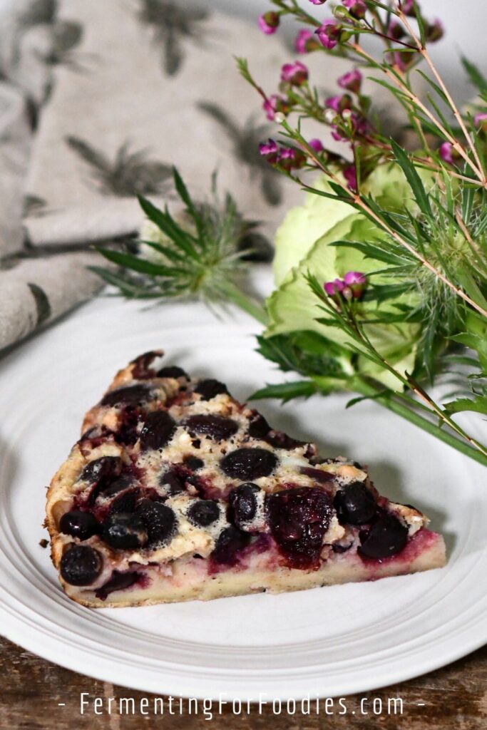 A slice of clafoutis with fermented cherries and blueberries